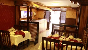 Un restaurante con mobiliario de madera, manteles blancos y servilletas rojas.