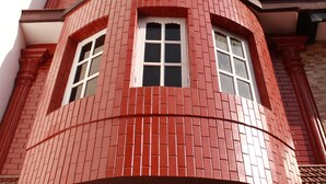 Un edificio en esquina con fachada de ladrillo rojo, múltiples ventanas y molduras blancas alrededor de las ventanas y el techo.