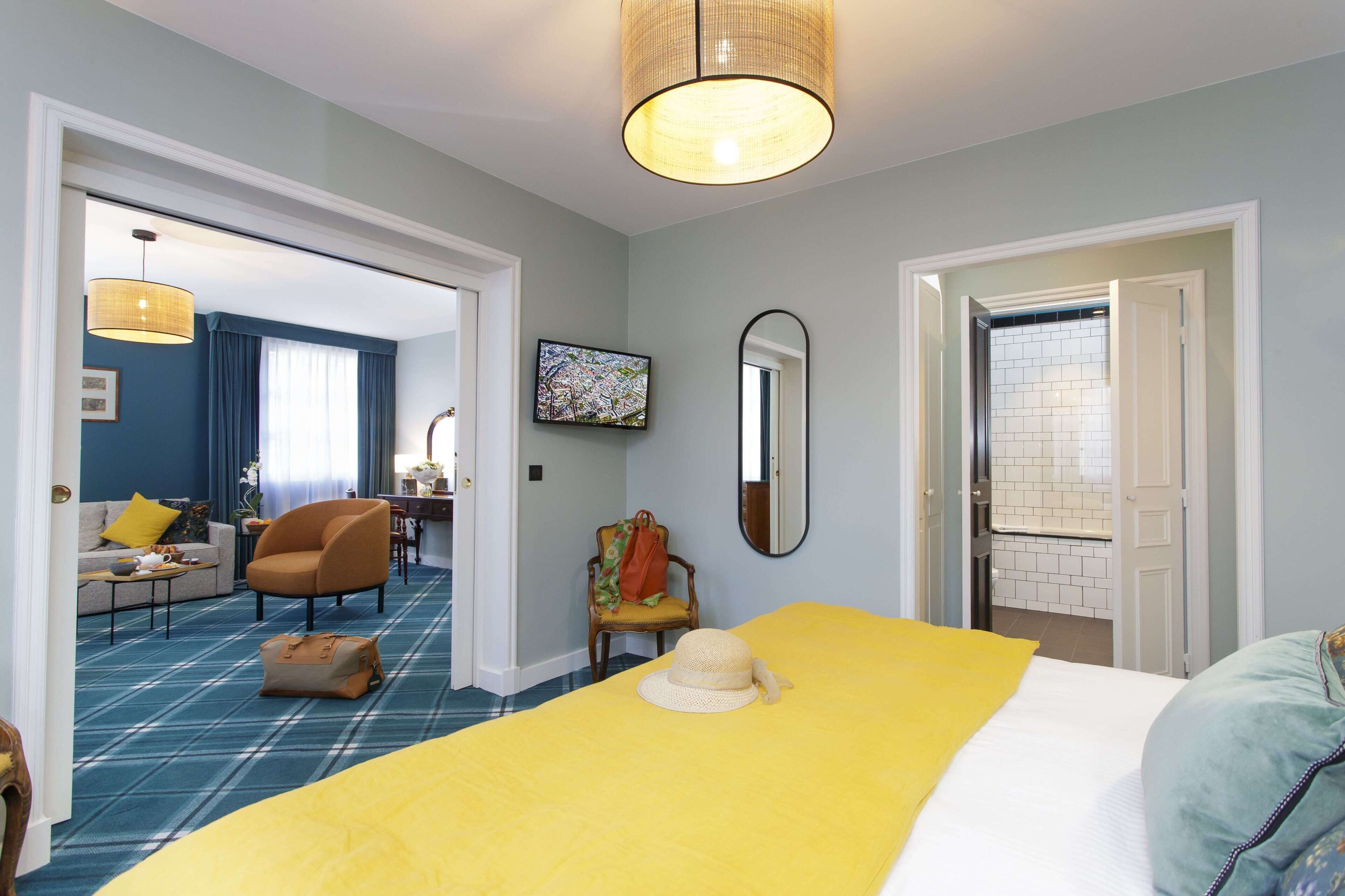 A hotel room with a bed, a chair, a television, and a bathroom visible through an open door.