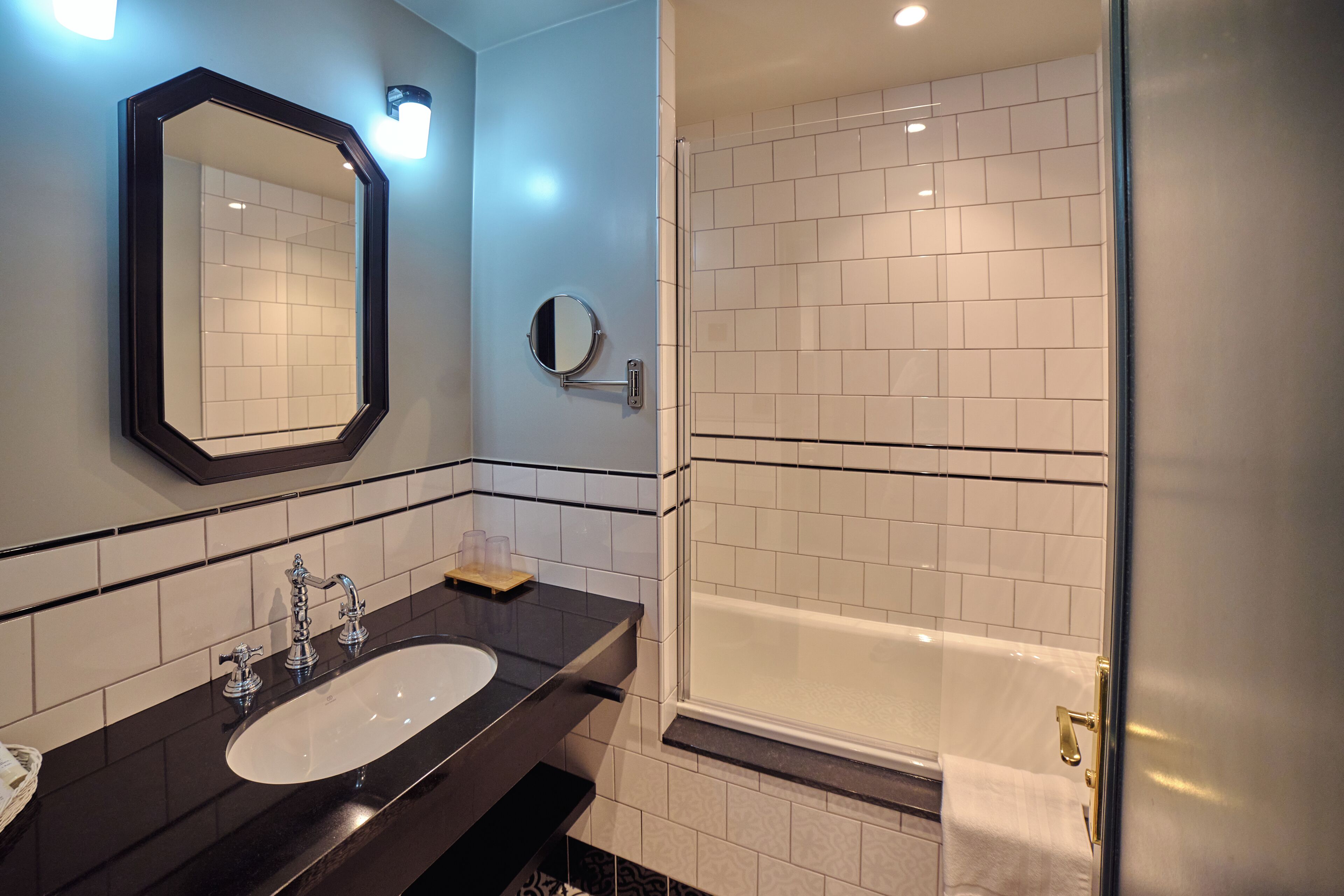 A bathroom with a large mirror, a sink, a bathtub, and a glass shower enclosure.