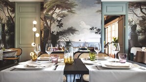 Mesa lista para cuatro personas con vista a un mural que representa un árbol y el cielo.