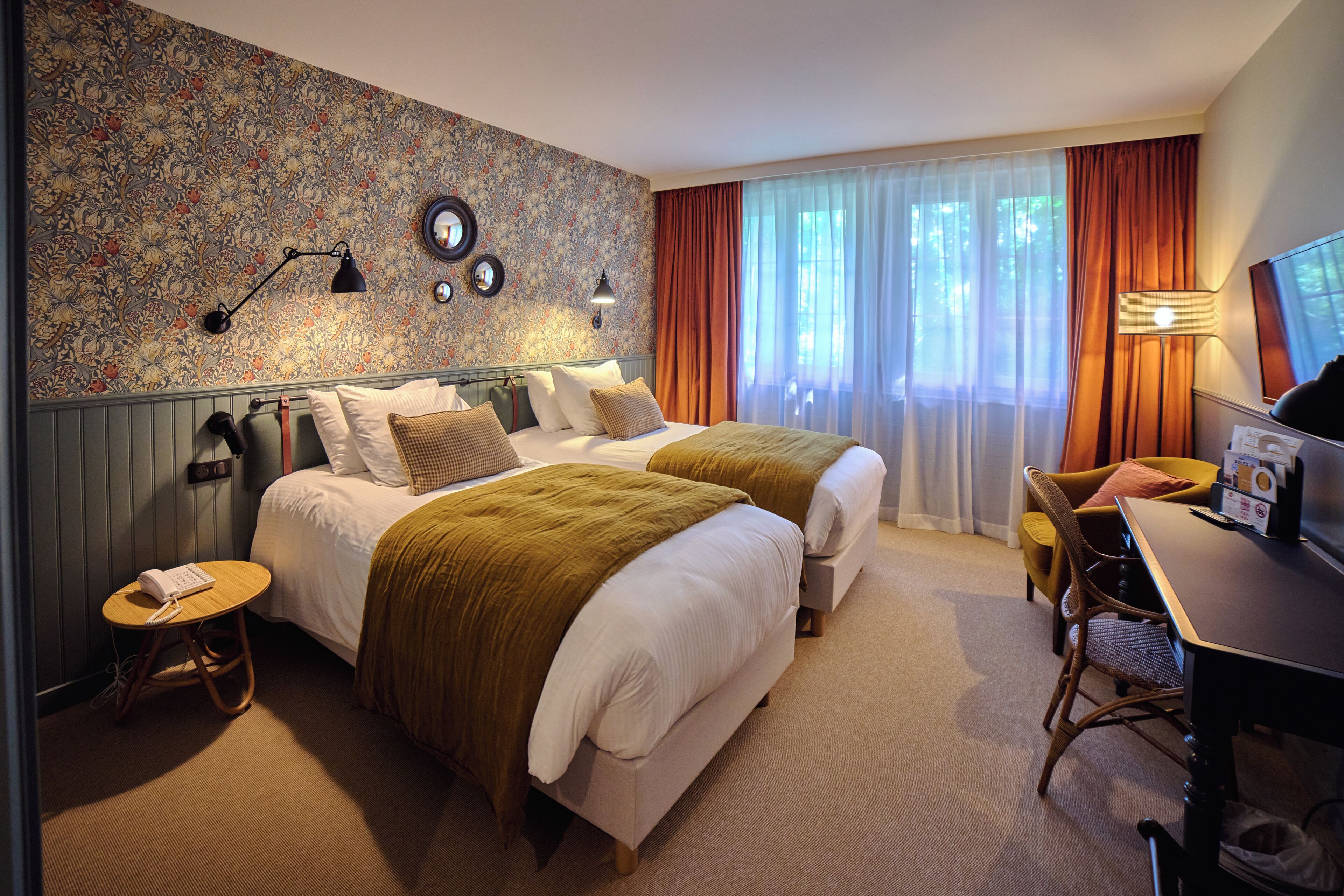 Een hotelkamer met twee bedden, een bureau, een stoel, een lamp en een televisie.