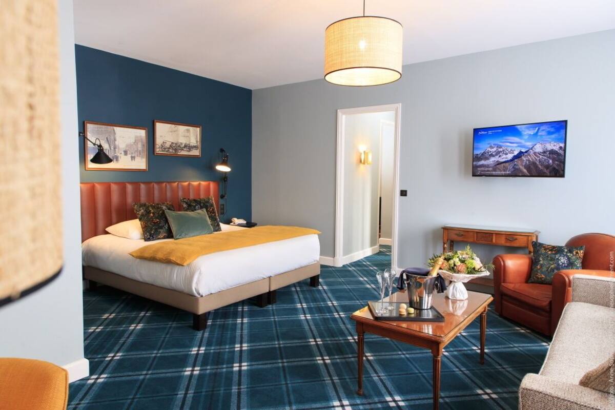 Ein Hotelzimmer mit Bett, Couchtisch, Sofa, Fernseher und einer Tür.