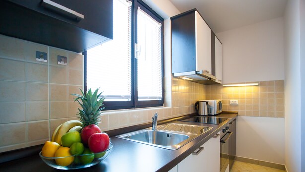 A kitchen with a fruit bowl, a sink, cabinets, and a window. - Urban Premium Apartments - Adults Only (Porec)