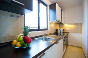 A kitchen with a fruit bowl, a sink, cabinets, and a window. - Urban Premium Apartments - Adults Only (Porec)