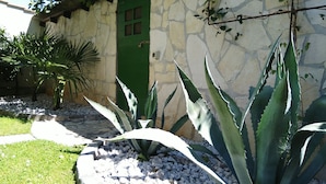 A stone building with a green door, surrounded by large agave plants and a palm tree. - Urban Premium Apartments - Adults Only (Porec)