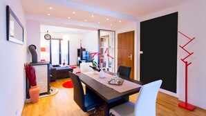 A modern dining area with a dark table, white chairs, and a red floor lamp. - Urban Premium Apartments - Adults Only (Porec)