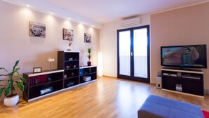 A modern living room with a wooden floor, a television, a bookshelf, and a potted plant. - Urban Premium Apartments - Adults Only (Porec)