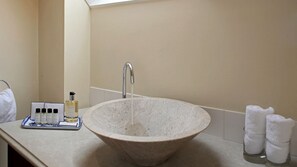 A stone sink with a faucet, a tray with toiletries, and towels on the counter. - Aintree Cottage (Chipping Norton)