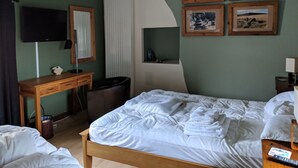 A hotel room with a bed, a desk, a chair, a TV, and framed pictures on the wall. - Weirholme Annex (Barnstaple)