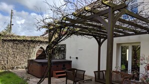 A patio with a wooden pergola, a hot tub, and wooden furniture. - Weirholme Annex (Barnstaple)