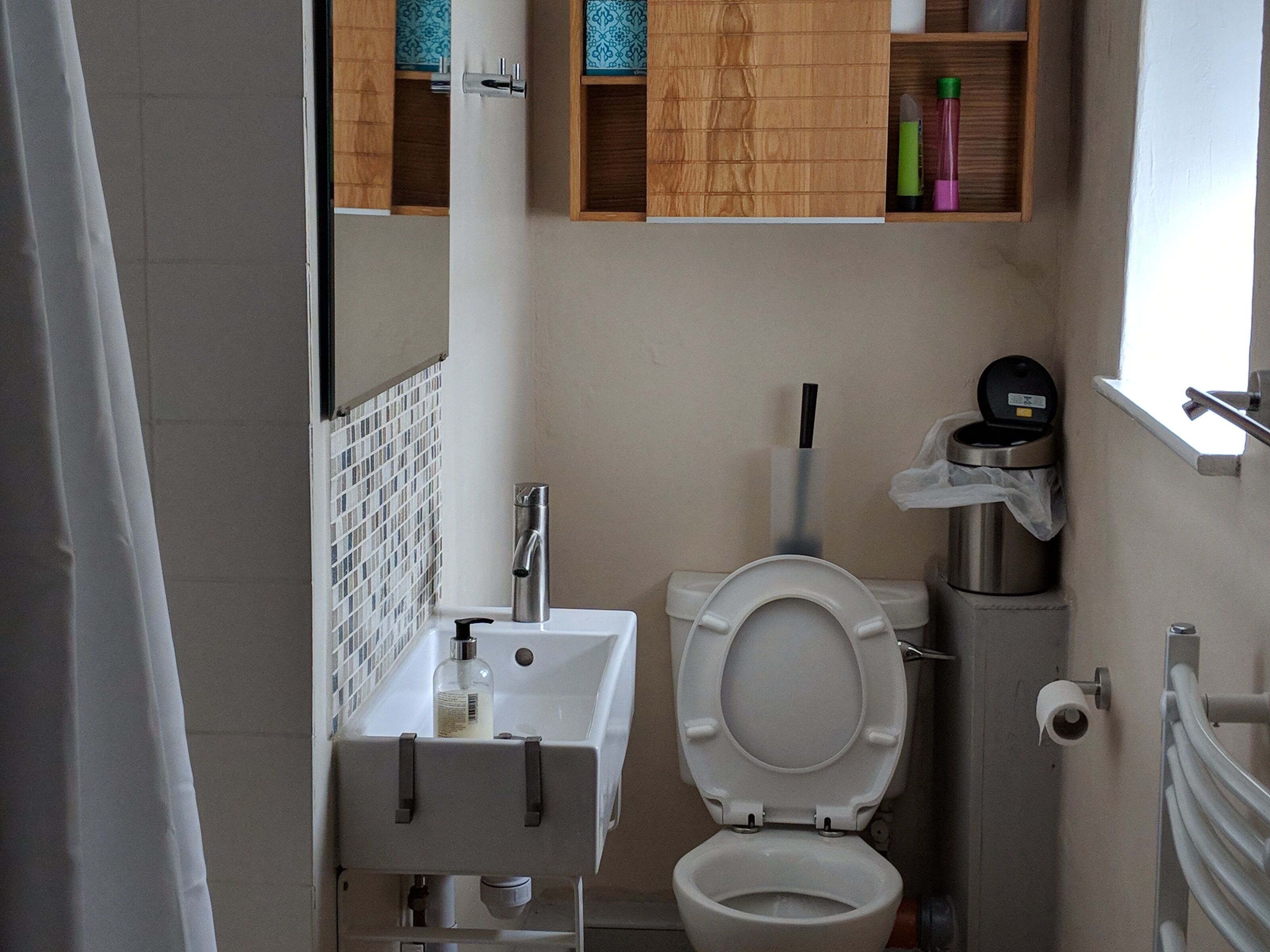 A bathroom with a toilet, sink, and storage cabinet.