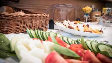 Une table de buffet garnie de divers légumes frais et un panier de pain.