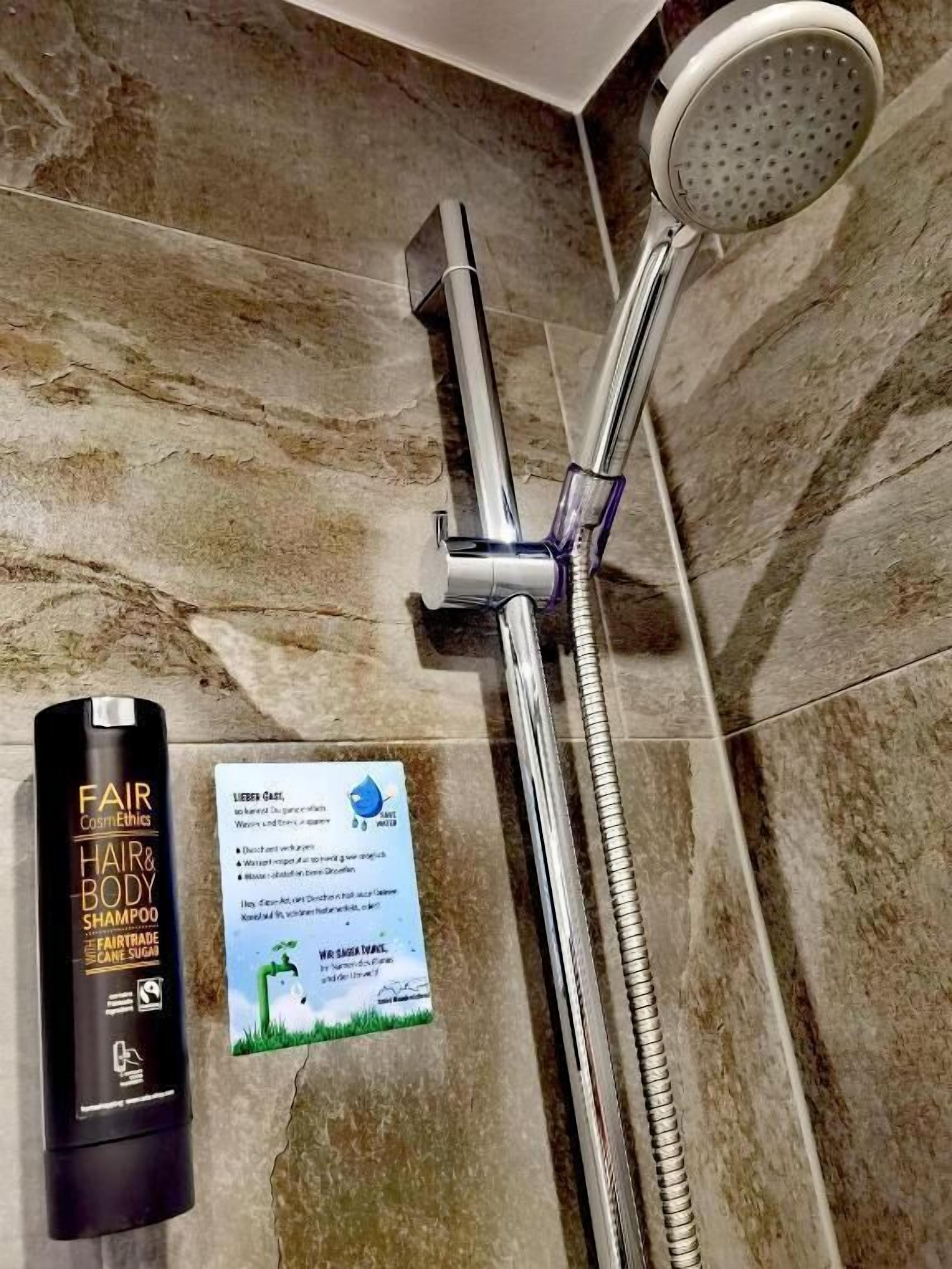 A bathroom with a shower, a bottle of shampoo, and a card.