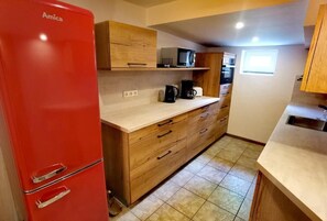 Cocina compacta con refrigerador rojo, armarios de madera, microondas y cafetera.