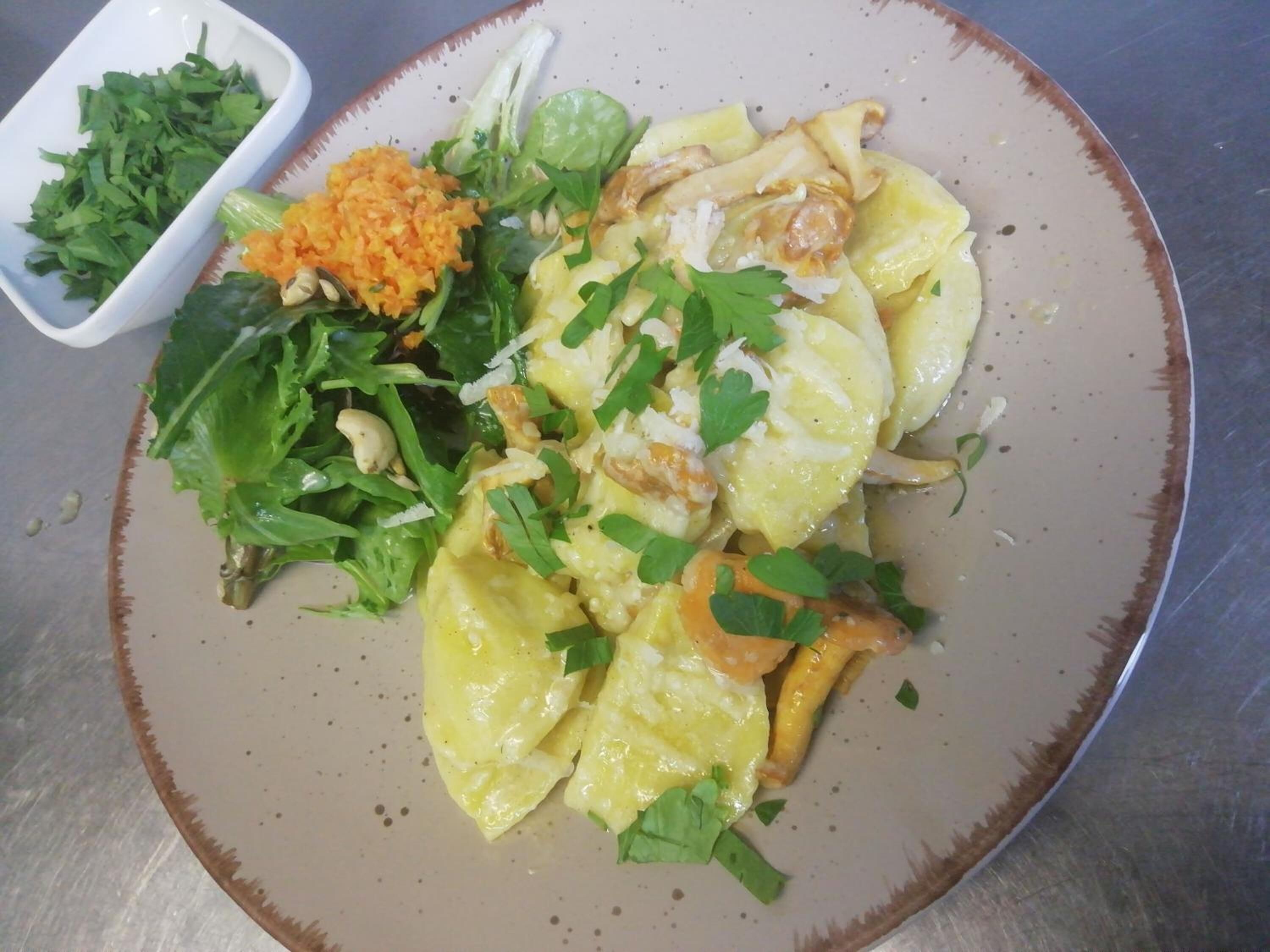 A plate of food with a side of greens and a small bowl of additional greens.