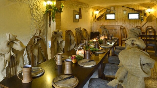 Une longue table à manger, décorée de bougies, d’assiettes et de carafes au style rétro.