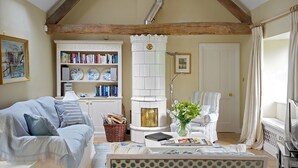 A cozy living room with a fireplace, a bookshelf, a sofa, and a chair. - Shipton Cottage (Chipping Norton)