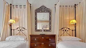 A double bed with a wooden dresser and a mirror between two curtains. - Shipton Cottage (Chipping Norton)