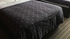 A hotel room with two beds, a nightstand, a lamp, and a window with curtains. - Warwick Lodge (Surbiton)