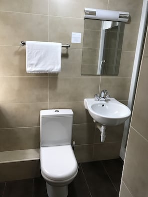 Un baño con inodoro, lavamanos y perchero para toallas.