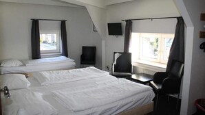 Une chambre d’hôtel avec deux lits, un bureau, une chaise, une télévision et une fenêtre avec des rideaux.