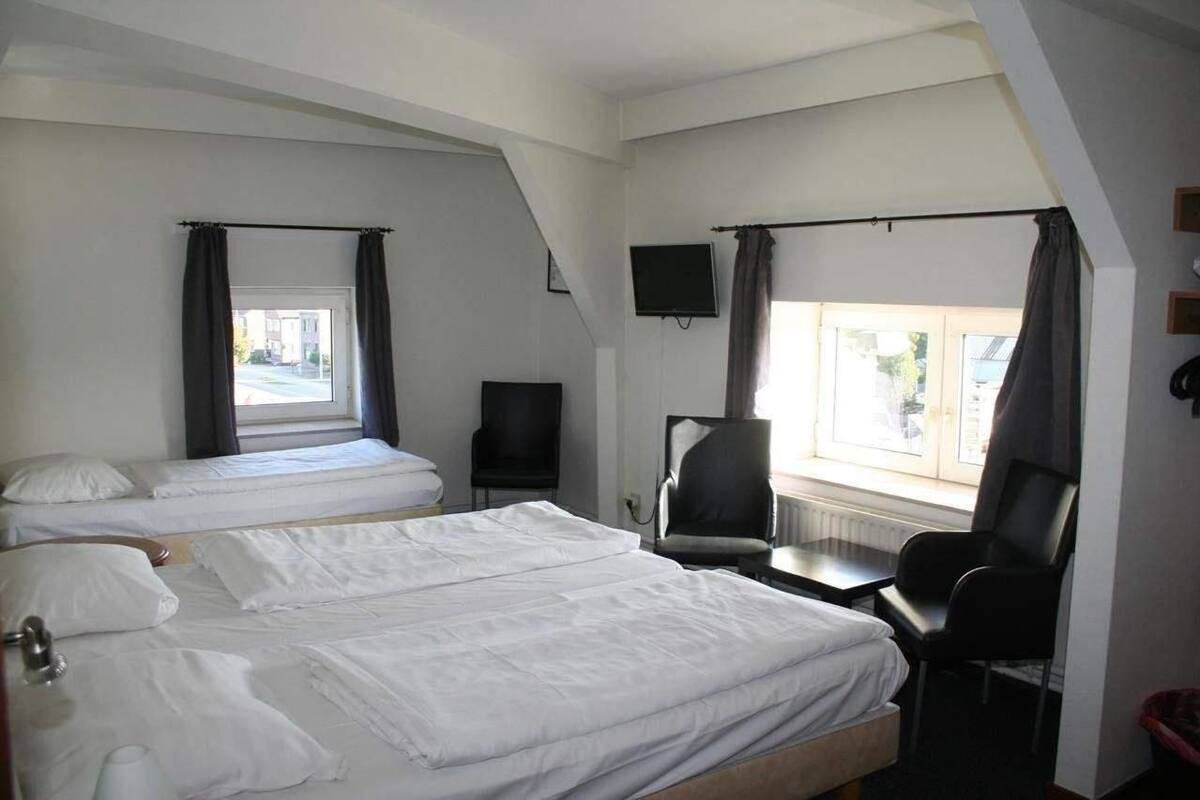 Habitación de hotel con dos camas, un escritorio, una silla, un televisor y una ventana con cortinas.
