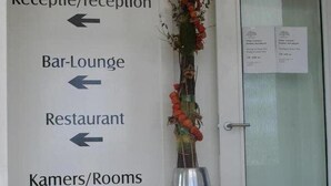 Un espace d’accueil d’hôtel avec des panneaux indicateurs menant à la réception, au bar, au salon et aux chambres.