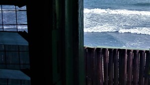 A view of the ocean through a window with a wooden frame and a view of the interior of a building with a tiled wall. - Rising Phoenix Magic Beach Resort (Accra)