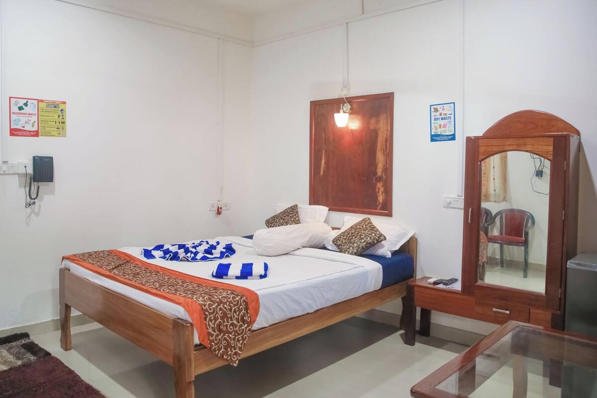 A neatly arranged bedroom with a wooden bed, a bedside table, a mirror, and a wardrobe.