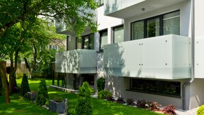 Un bâtiment moderne doté d’un toit plat, de grandes fenêtres et d’un jardin bien entretenu, agrémenté de divers arbustes et d’une pelouse.