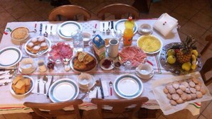 Una mesa de comedor dispuesta con platos, tazones, cubiertos y diferentes alimentos.