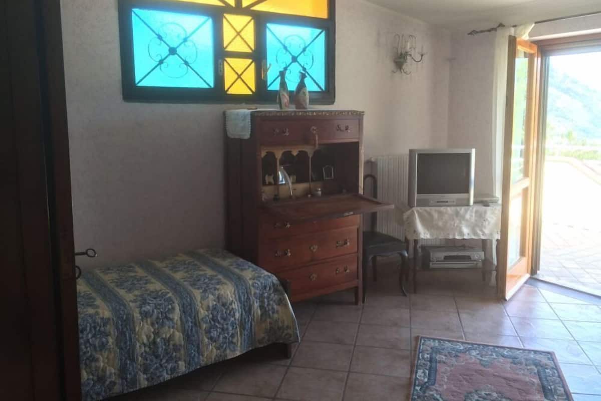 Een kamer met een bed, een dressoir, een televisie en een raam met uitzicht.