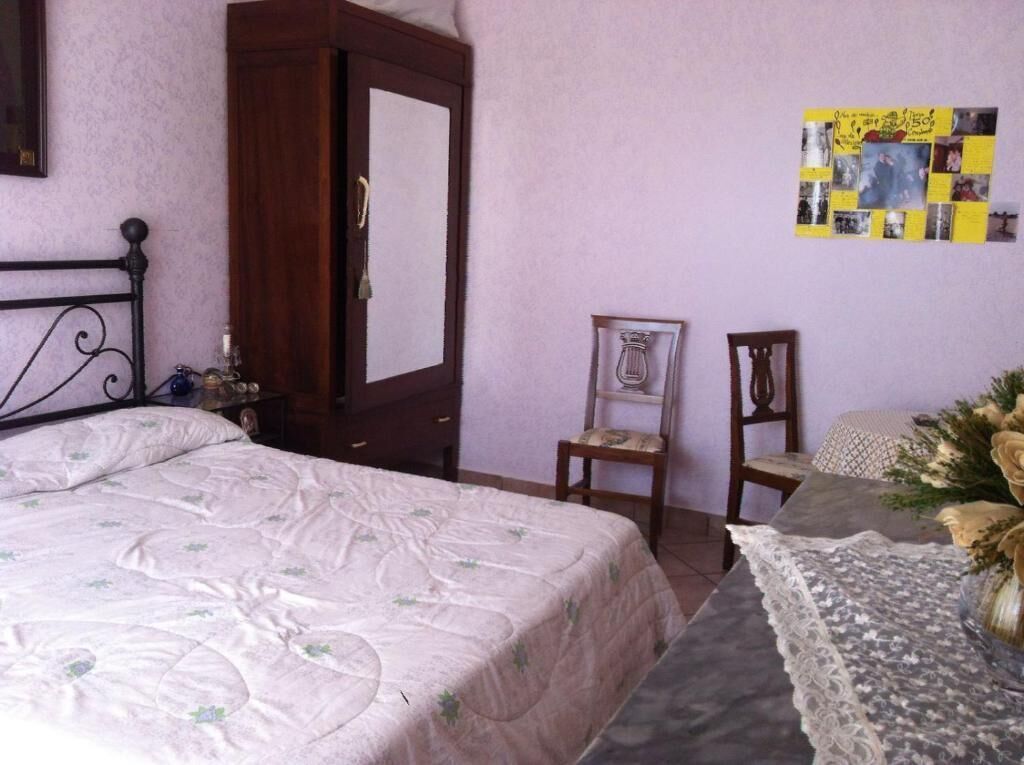 Un dormitorio con una cama, una silla, un escritorio y una pared con un tablón de anuncios.