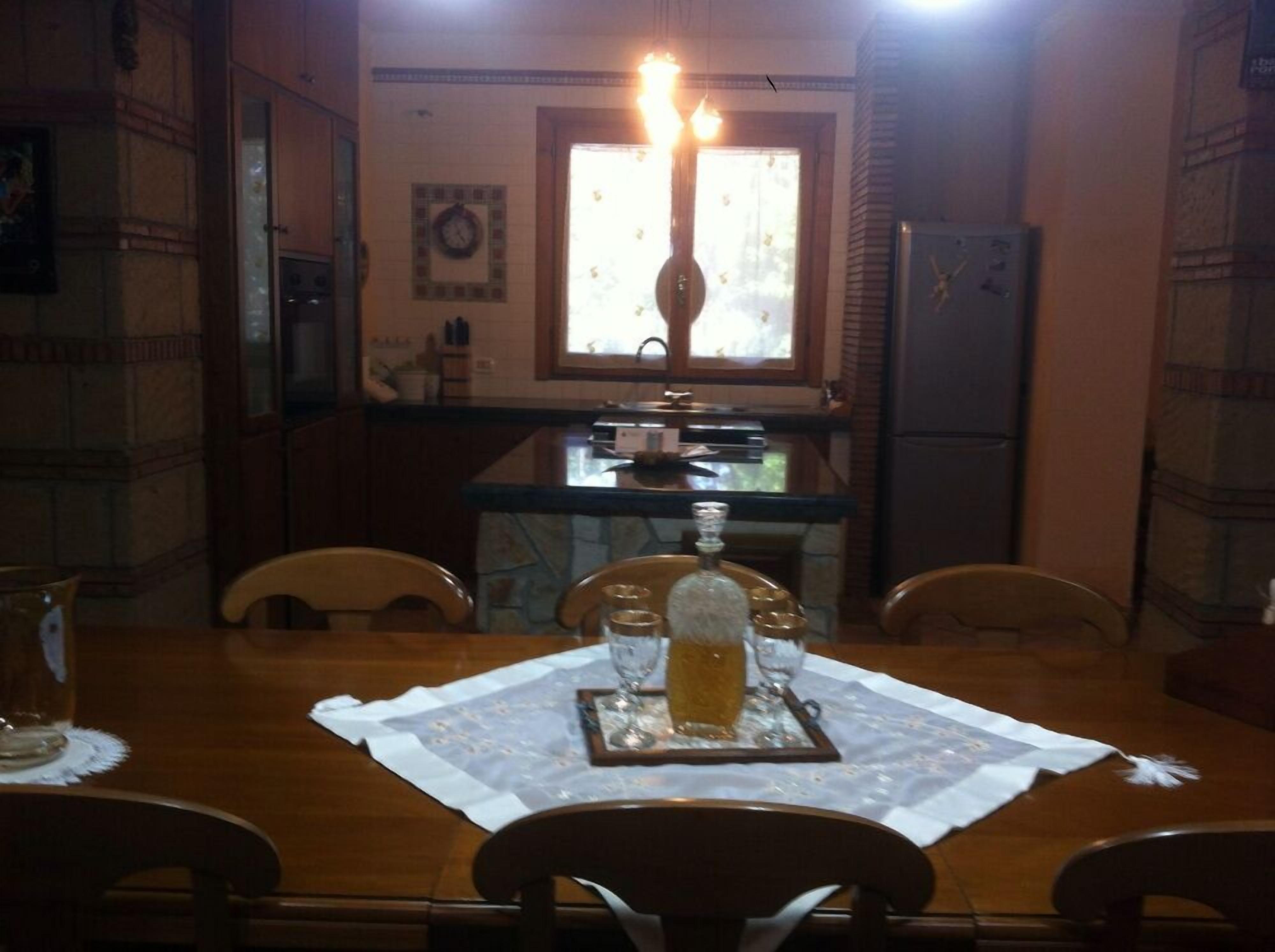 A dining area with a table set for two, a chandelier, and a window with curtains.