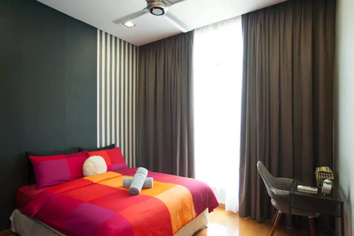 Een hotelkamer met een bed, een stoel, een bureau en een plafondventilator.