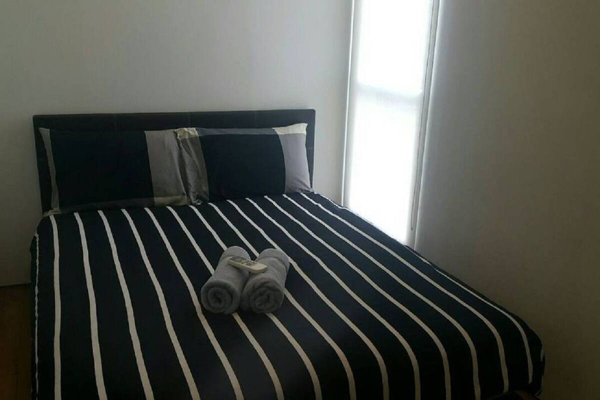 Een bed met gestreepte lakens, kussens en opgerolde handdoeken.
