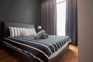 A neatly made bed with striped bedding, a fluffy pillow, and rolled towels. - KL101 Service Suite at Soho Suites KLCC (Kuala Lumpur)