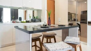 A modern kitchen with a central island, bar stools, and a wooden door.