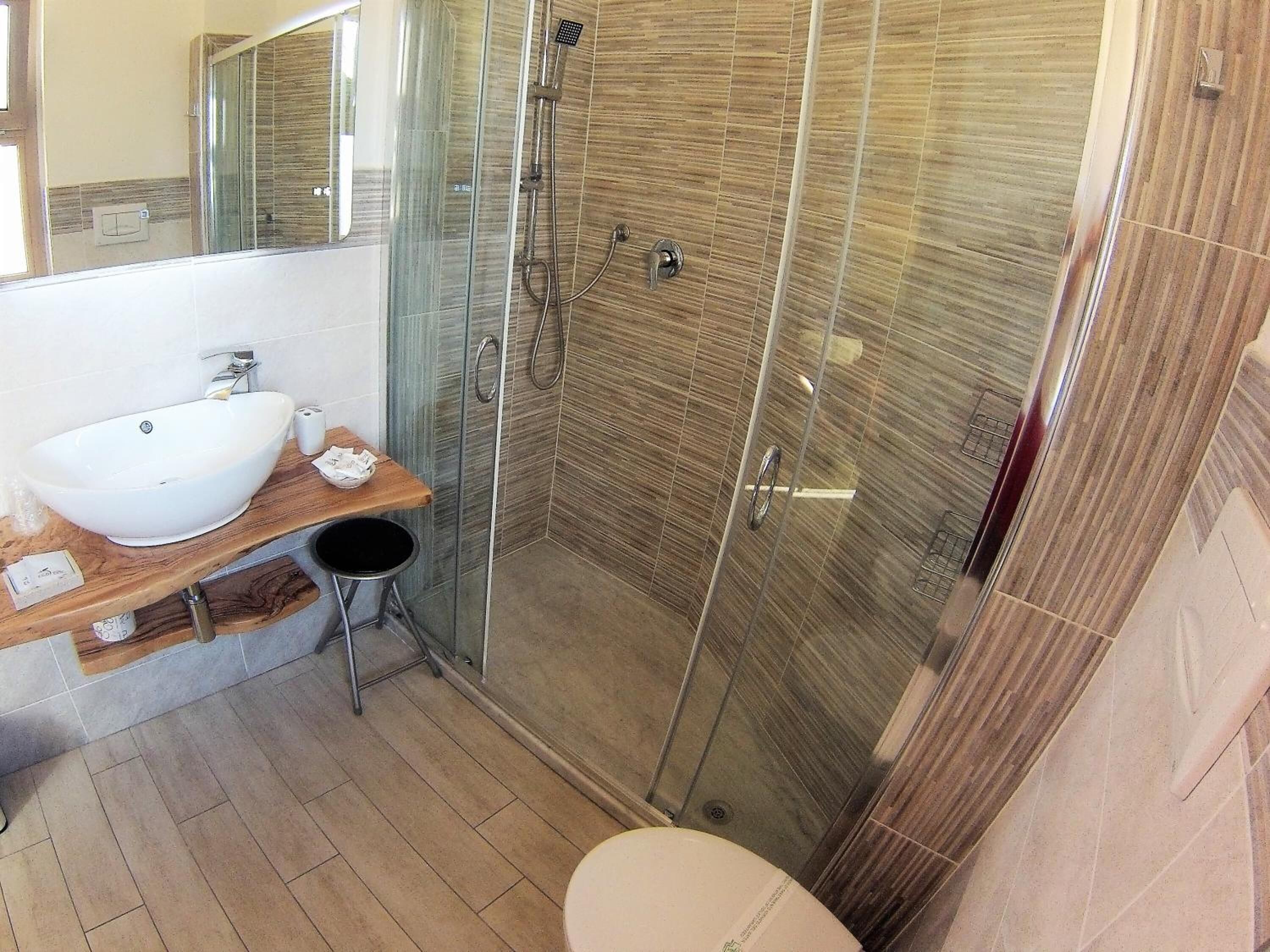 A modern bathroom with a glass-enclosed shower, a white sink, and a wooden vanity.