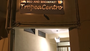 A sign for a bed and breakfast named TropeaCentro, with a hallway leading to a room with a ceiling fan and potted plants. - Tropeacentro (Tropea)