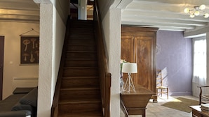 A wooden staircase leading to an upper floor, flanked by textured walls and a wooden door. - Chambres d'hôtes Le Puy d'Anché (Sauzé-Vaussais)