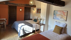 A room with two beds, wooden beams, a desk, and a chair. - Chambres d'hôtes Le Puy d'Anché (Sauzé-Vaussais)