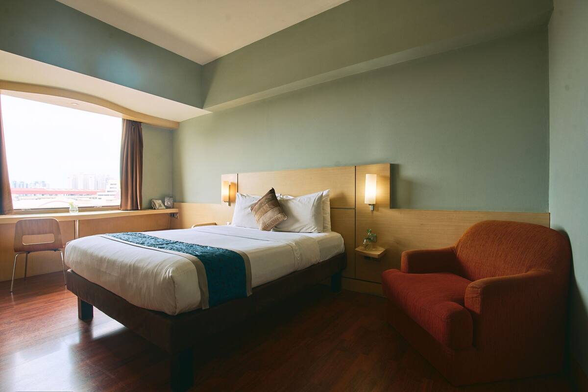 A hotel room with a large bed, a desk, and a chair.