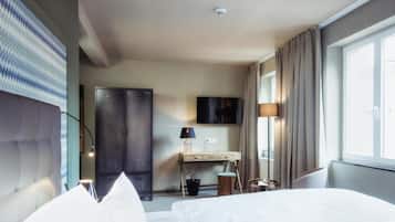 Une chambre d’hôtel équipée d’un lit, d’un bureau, d’une télévision et d’une armoire.