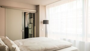 Een hotelkamer met een bed, een garderobe en een vloerlamp.
