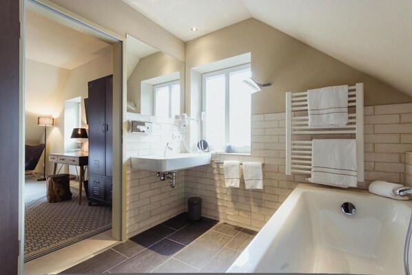 A modern bathroom with a large bathtub, a vanity with a mirror, and a window providing natural light.
