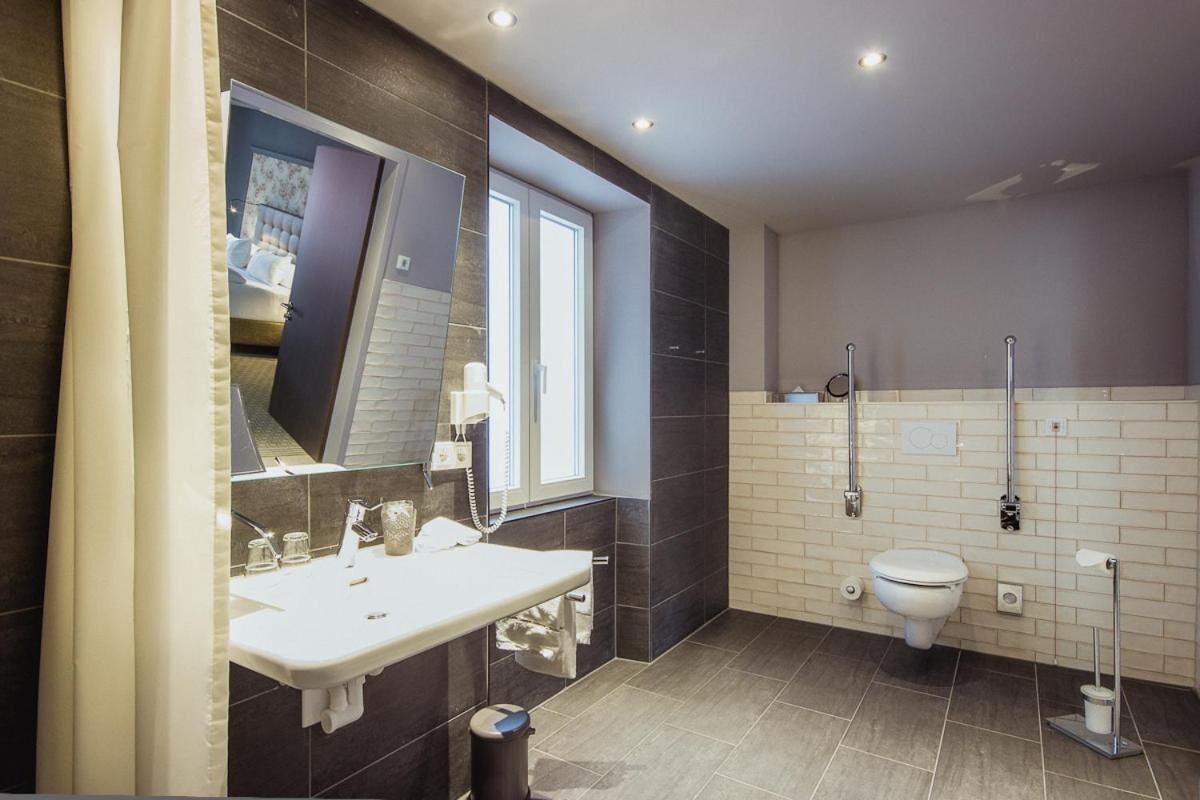 A modern bathroom with a large mirror, a sink, a toilet, and a shower area.