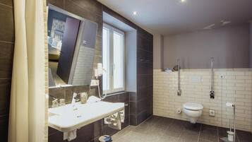 A modern bathroom with a large mirror, a sink, a toilet, and a shower area.