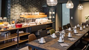 Een restaurant met een lange houten tafel, gedekt voor een maaltijd, omringd door stoelen.
